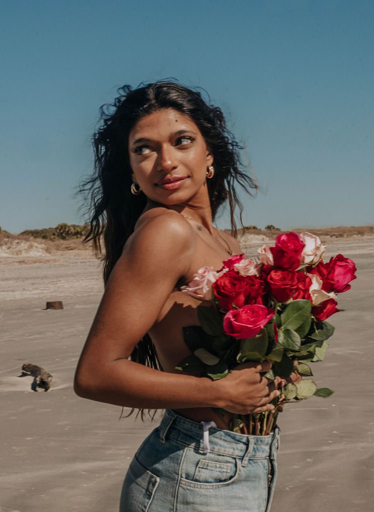 Coach is posing holding a bouquet of flowers.